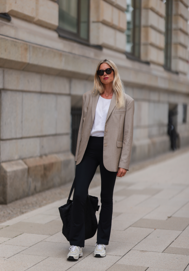 mujer vestida para ir a la oficina con americana, pantalón negro, camiseta y zapatillas deportivas
