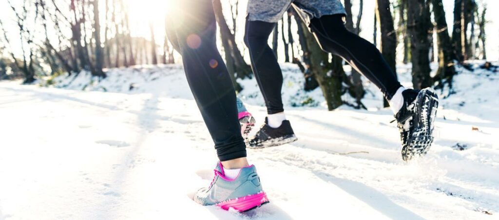 mujer y hombre corren en la nieve