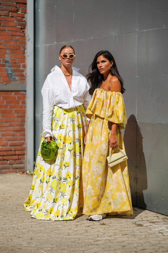 Mujeres con looks primaverales: una camisa blanca oversize, falda de flores y un vestido amarillo con estampado floral y zapatillas